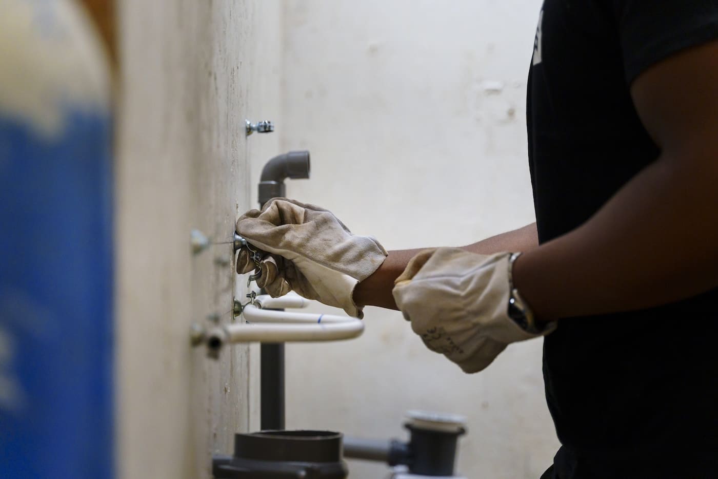 apprenant en atelier de plomberie qui installe une canalisation murale pour préparer son cap plombier chauffagiste en alternance