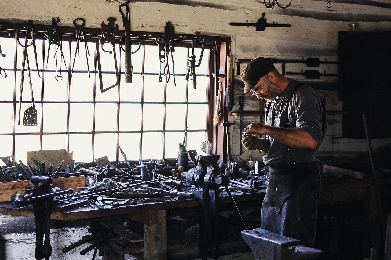 Artisan travaillant dans son atelier, mains sur l'établi et outils au mur