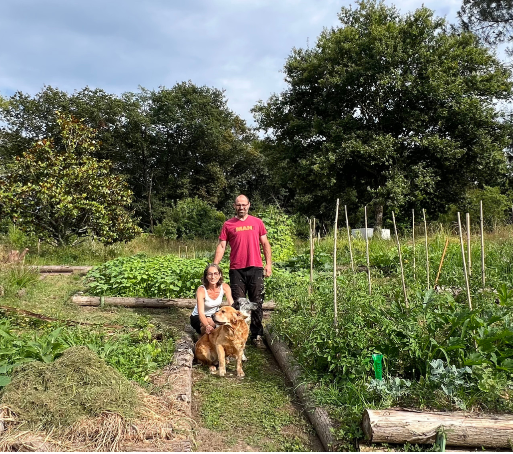 Karine, Frédéric et leurs deux chiens au milieu de leur potager